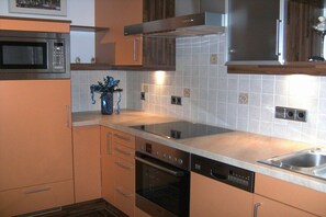 Eine Küche mit Mikrowelle, Backofen, Geschirrspüler und einer Edelstahl-Spüle.