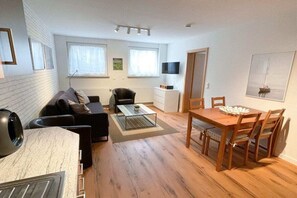 A modern living room with a sofa, coffee table, and dining table. - Holiday apartment with 1 bedroom (Ostseebad Sellin)