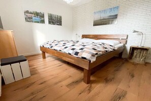 Ein Schlafzimmer mit einem Holzbett, einer weißen Ziegelwand und einem Holzboden.