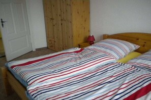 A bedroom with a bed, a wooden wardrobe, and a nightstand with a lamp. - Holiday apartment with 1 bedroom (Zehdenick)