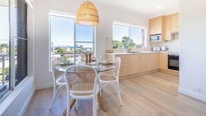 Una cucina moderna con zona pranzo, ampie finestre e vista all'esterno.