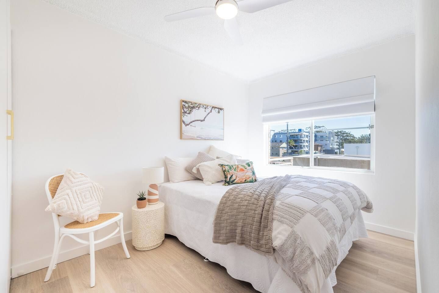 A bedroom with a bed, a chair, a window, and a ceiling fan.