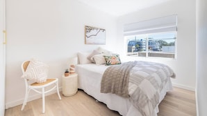 Una camera da letto con un letto, una sedia, una finestra e una ventola a soffitto.