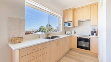 A modern kitchen with a large window, wooden cabinets, a microwave, a toaster, and a dishwasher.