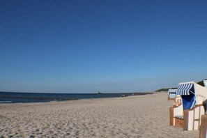 A beach with rows of beach chairs and umbrellas, a clear sky, and the ocean in the background. - Holiday home with 2 bedrooms (Ostseeheilbad Zingst)