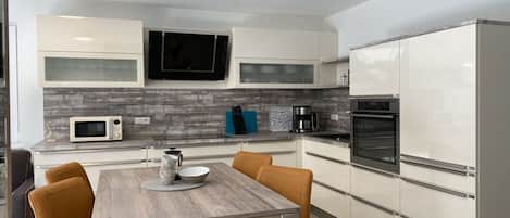Cozinha moderna com armários brancos, micro-ondas, máquina de café e forno embutido.