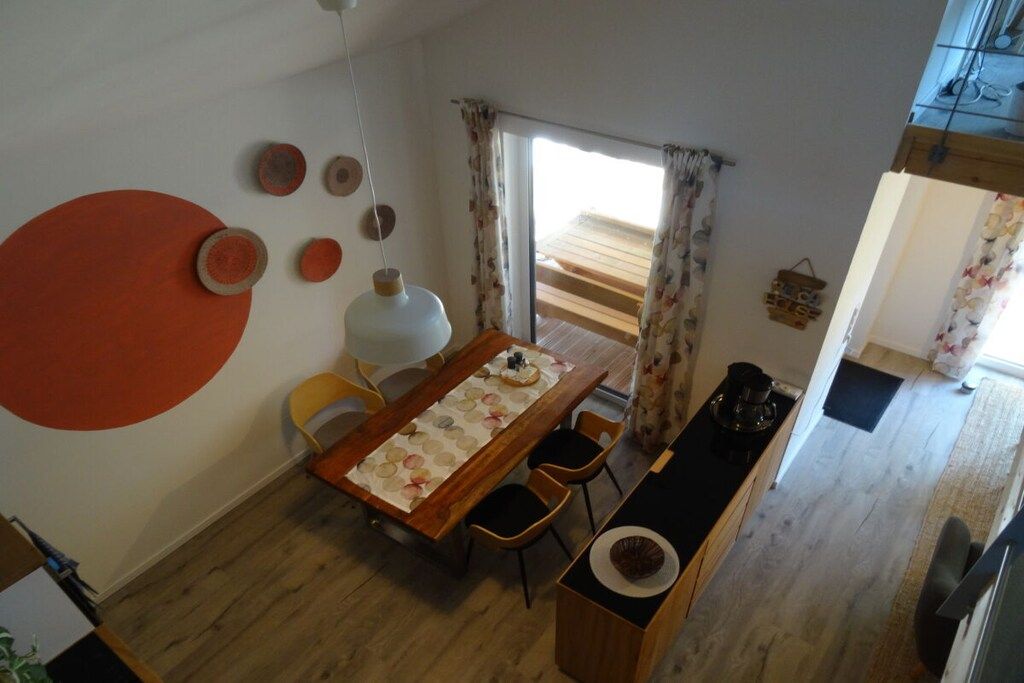 Un coin repas avec une table en bois, des chaises et une grande fenêtre agrémentée de rideaux.