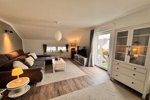 Ein stilvolles Wohnzimmer mit Sofa, Couchtisch, Fernseher und Schrank.