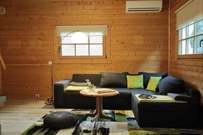A cozy room with a wooden interior, a black sofa, a small round table, and a window with a view. - Holiday home in Canow with swimming pool (Canow)