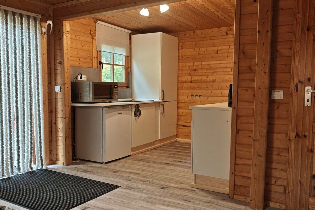 A compact kitchen with a microwave, refrigerator, and cabinets.
