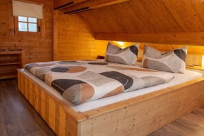 A wooden cabin bedroom with a bed, pillows, and a window. - Holiday home in Canow with swimming pool (Canow)
