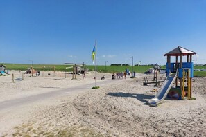 A sandy beach with a playground, including a slide and a small pavilion. - Holiday apartment with 1 bedroom (Butjadingen)