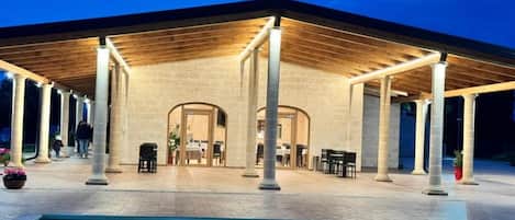 A covered outdoor area with a pool, columns, and tables.