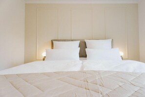 Ein ordentlich bezogenes Bett mit einer gesteppten Decke und zwei Nachttischlampen.