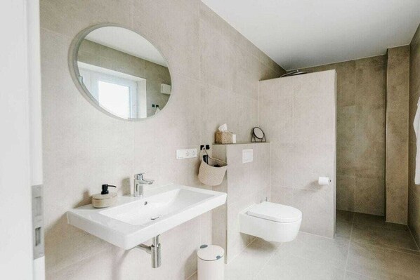 Ein modernes Badezimmer mit einem großen Waschbecken, Toilette und Spiegel.