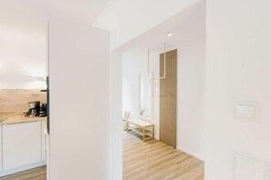 Ein modernes Interieur mit Holzboden, weißen Wänden und einer Küchenzeile inklusive Kaffeemaschine.