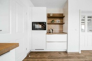 A compact kitchen with white cabinetry, a wooden countertop, and a built-in microwave. - Holiday home with 3 bedrooms (Greetsiel)