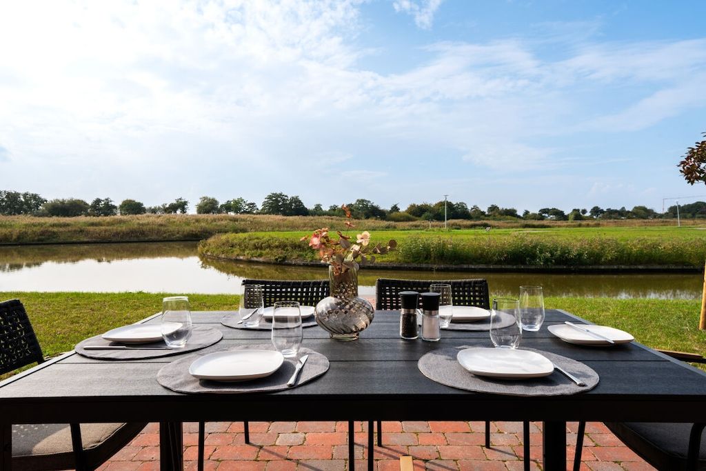 A table set for dining with a view of a lake and greenery.