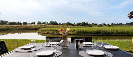 Mesa lista para comer con vista a un lago y follaje.