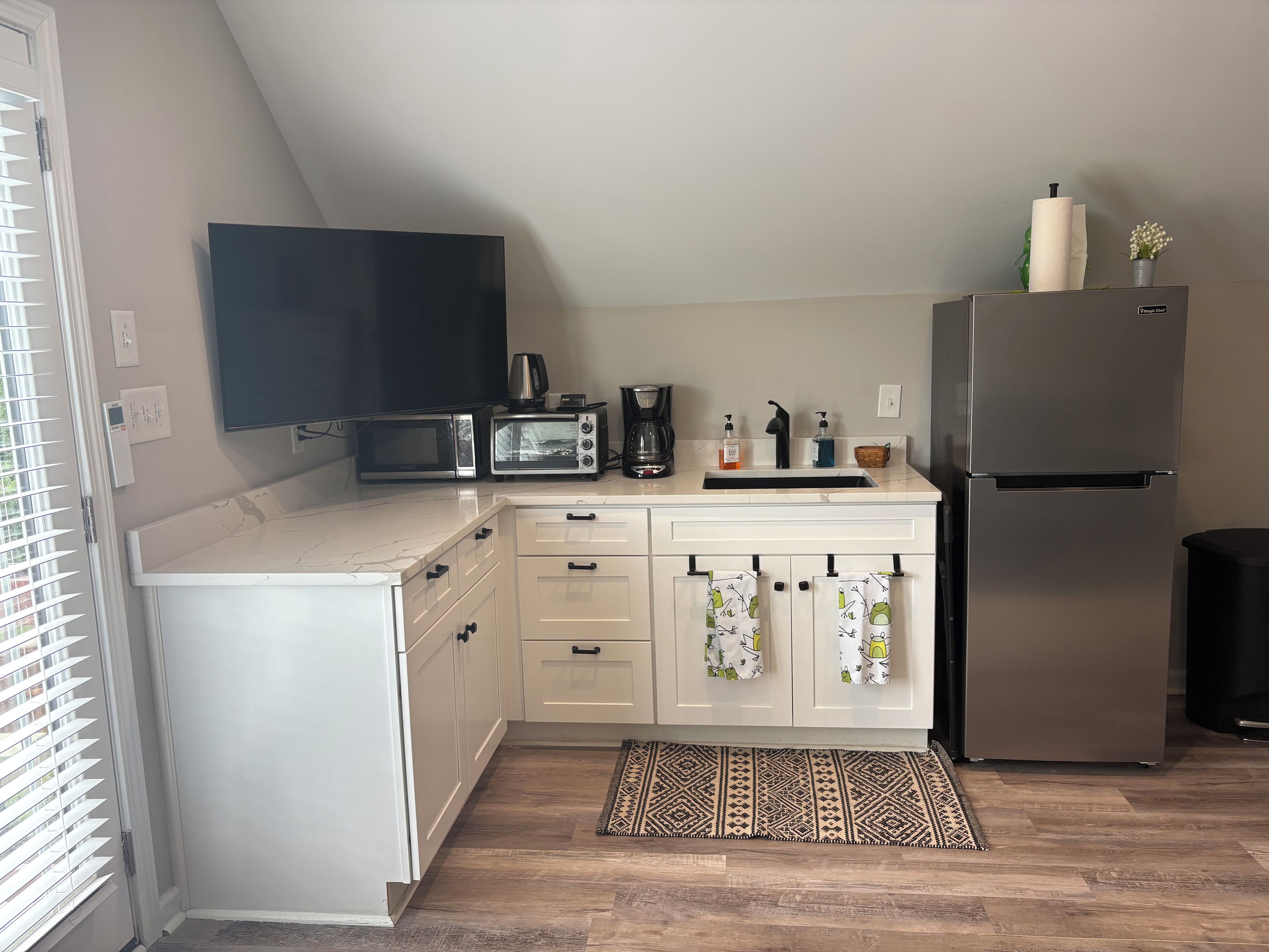Una cocina compacta equipada con microondas, tostadora, cafetera y refrigerador.