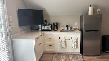 Une cuisine compacte équipée d’un four à micro-ondes, d’un grille-pain, d’une machine à café et d’un réfrigérateur.