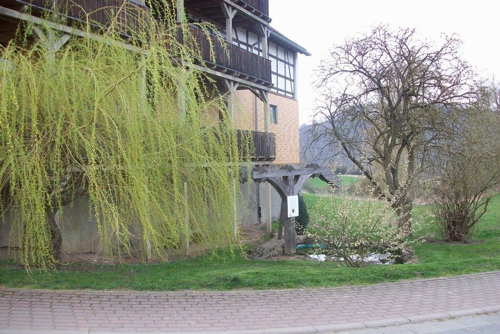 Ein Gebäude mit Balkon, Steinmauer und Baum.