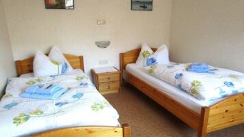 Ein Doppelzimmer mit zwei Holzbetten, jeweils mit Kissen und einem gefalteten Handtuch.