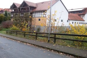 Un barrio residencial con un camino pavimentado, una valla de madera y casas de arquitectura tradicional.