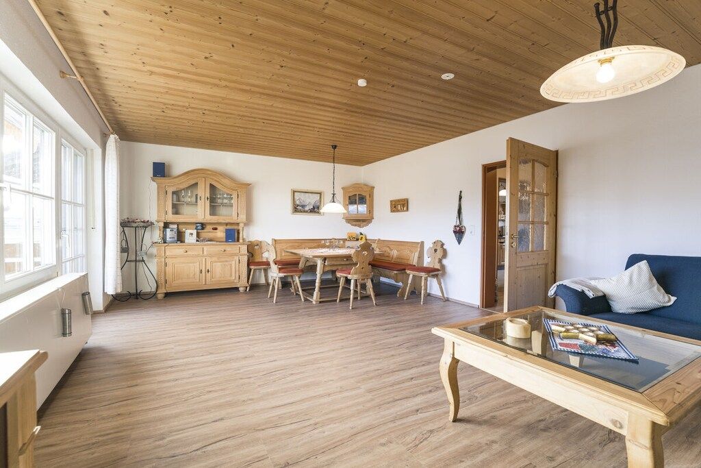 Ein geräumiger Raum mit Holzboden, einem Essbereich mit Holztisch und -stühlen, einem Sofa und einem Couchtisch.