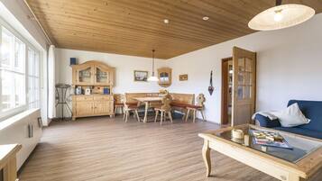 Ein geräumiger Raum mit Holzboden, einem Essbereich mit Holztisch und -stühlen, einem Sofa und einem Couchtisch.
