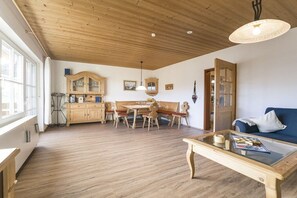 Ein geräumiger Raum mit Holzboden, einem Essbereich mit Holztisch und -stühlen, einem Sofa und einem Couchtisch.
