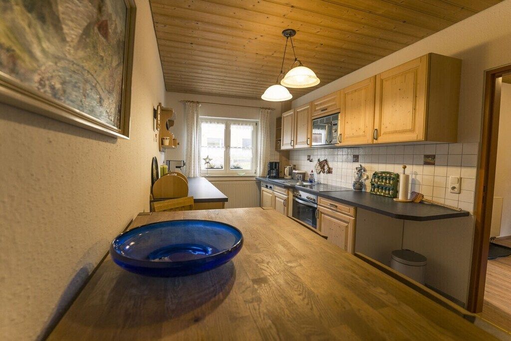Eine Küche mit Holzausstattung, einer blauen Schüssel auf der Arbeitsplatte und einer Pendelleuchte.