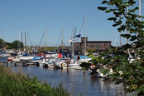 A marina with multiple boats docked, a building in the background, and a clear sky. - Holiday home in Wittmund with swimming pool (Wittmund)