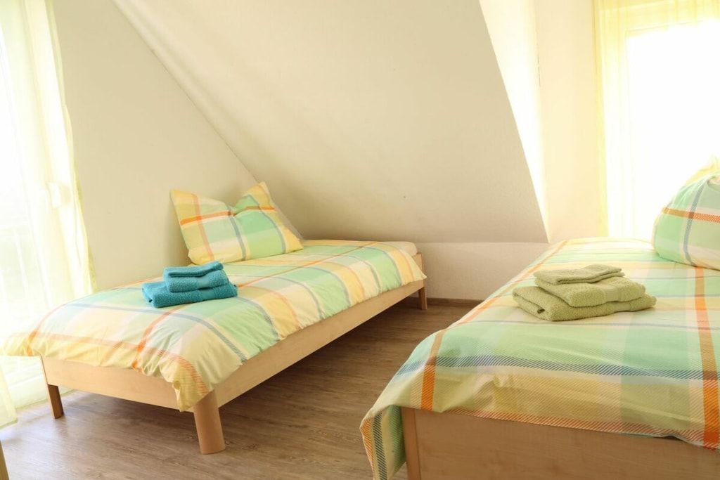 A bedroom with two beds, each with a plaid bedspread and pillows.