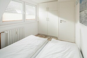 A bedroom with a bed, a wardrobe, and a radiator. - Holiday apartment with 1 bedroom (Norderney)