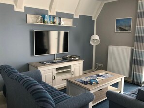 A living room with a flat-screen TV, a sofa, a coffee table, and a radiator. - Dream Berth Boatswain (Wittmund)