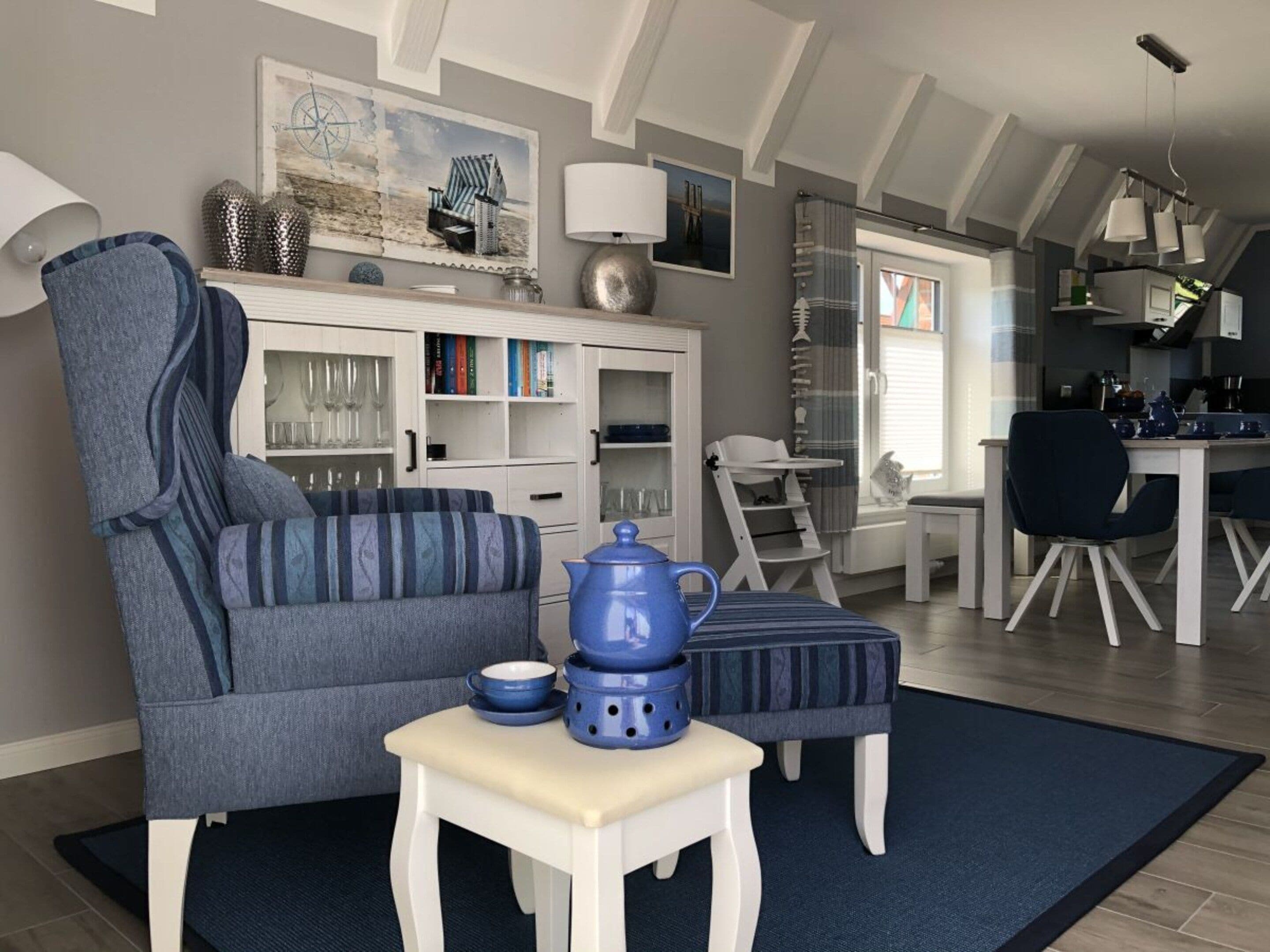 Un salon comprenant un canapé, une petite table, une chaise haute et un coin cuisine avec une table à manger.