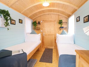 Ein Zimmer mit zwei Betten, Holzwänden und -decke sowie einer Tür.