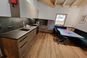 A compact kitchen with wooden cabinets, a sink, and a dining area with a table and chairs.