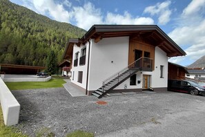 A two-story building with a wooden staircase and a balcony. - Modern holiday apartment in a quiet location (Längenfeld)