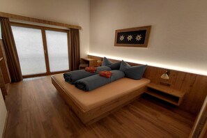 A room with a bed, a nightstand, a lamp, and a window with curtains.