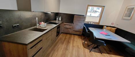 A compact kitchen with wooden cabinets, a sink, and a dining area with a table and chairs.