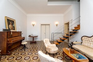A spacious living room with a grand piano, a sofa, a chair, and a staircase. - La Terrazza nel Blu | Sea View (Piano di Sorrento)
