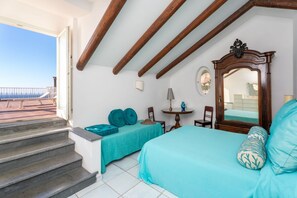 A bedroom with a bed, a chair, a table, and a window with a view of the sea. - La Terrazza nel Blu | Sea View (Piano di Sorrento)