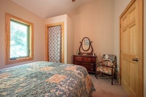 A bedroom with a bed, dresser, chair, and a door. - Escape to 8 private acres in Floyd County with Little River views and direct private river access. Enjoy fishing, kayaking, private trails, high-speed WiFi, a dedicated workspace, a kids' area and plenty of room to relax in nature. (Floyd)