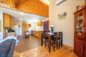 A spacious living area with a wooden ceiling, a dining table with chairs, a kitchen in the background, and a couch. - Escape to 8 private acres in Floyd County with Little River views and direct private river access. Enjoy fishing, kayaking, private trails, high-speed WiFi, a dedicated workspace, a kids' area and plenty of room to relax in nature. (Floyd)