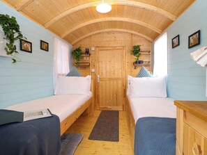 Eine Holzhütte mit zwei Etagenbetten aus Holz, einer Holzzahlendecke und einer Tür mit Griff.
