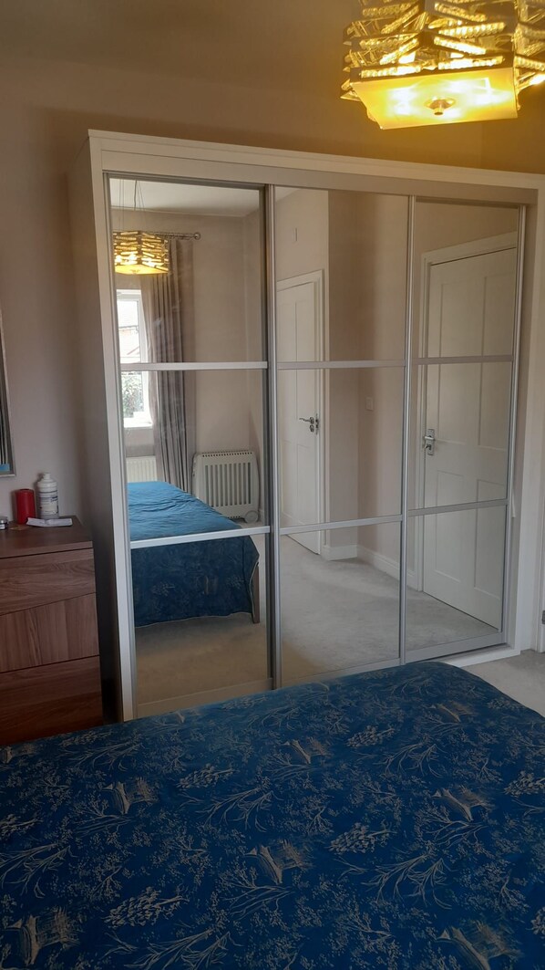 A bedroom with a bed, a dresser, a wardrobe, and a radiator.