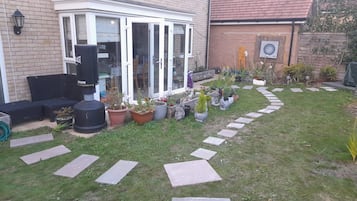 A residential garden with a patio, potted plants, and stepping stones.