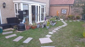 A residential garden with a patio, potted plants, and stepping stones.